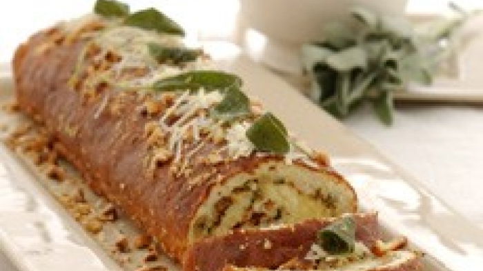 a picture of a cooked roulade on an oblong plate with a dish of sauce next to it