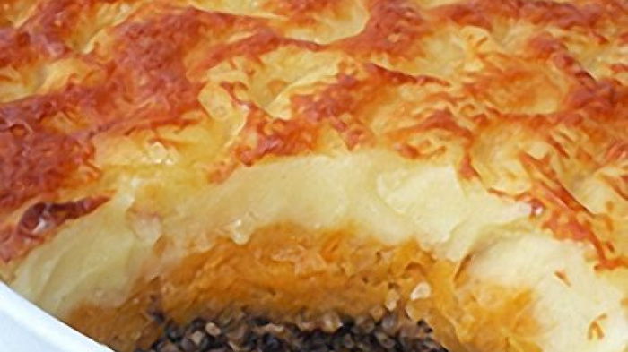 haggis pie in a white dish with a portion removed showing the filling of haggis, swede and potato