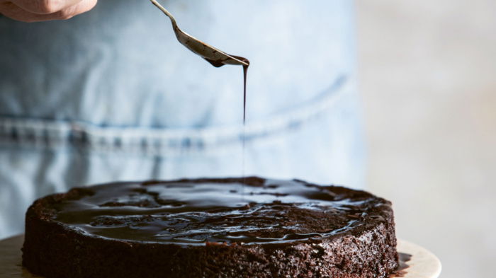 a picture of a chocolate and almond cake on a marble cake stand 