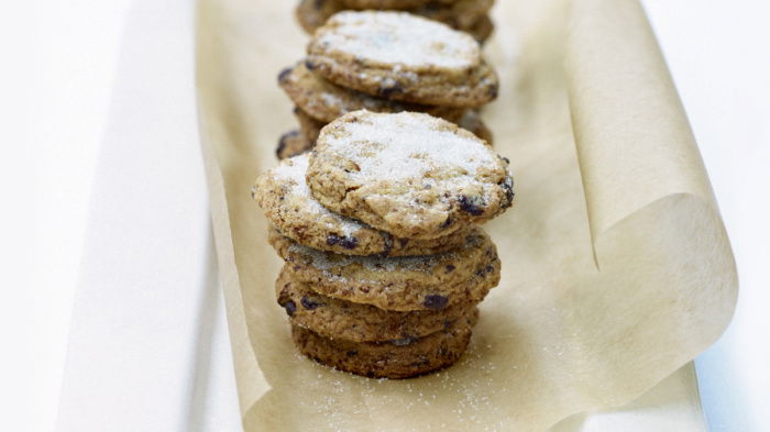 Little piles of cooked biscuits on a sheet of greaseproof paper with icing sugar sifted on the top