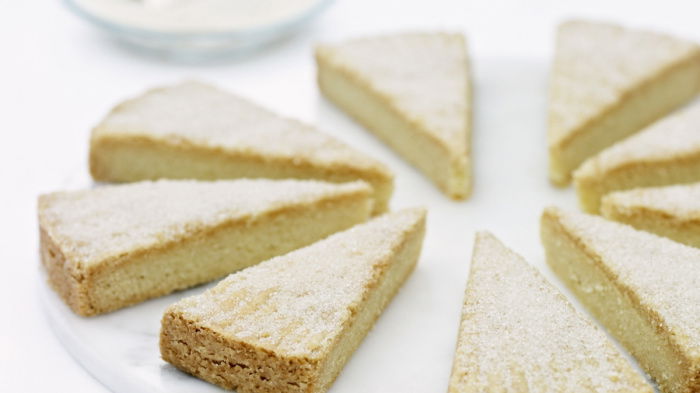Eight slices of shortbread dusted with sugar on a whilte marble plate