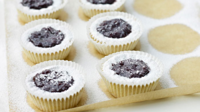 Six little Viennese Tartlets on a sheet of greaseproof paper with sifted icing sugar sprinkled over the top