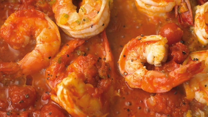 Close-up of a dish featuring prawns in a rich, tomato sauce giving a vibrant and appetising appearance.