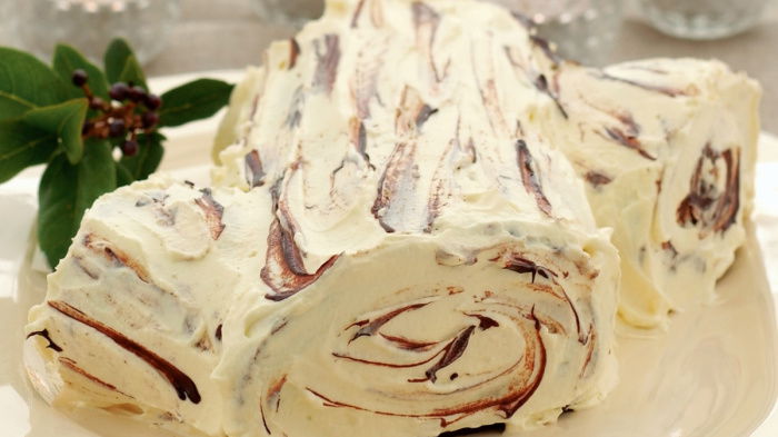a picture of a Chocolate Chestnut Log made of white chocolate log on a cream plate with glass tea lights in the background