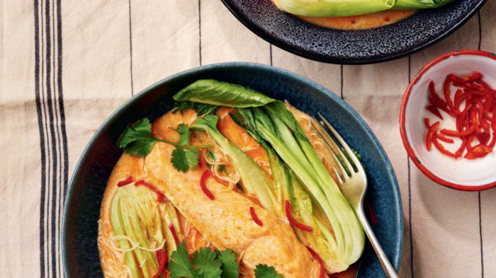 a picture of a bowl of soup with salmon fillets, noodles and pak choi next to a little dish of sliced red chillis 