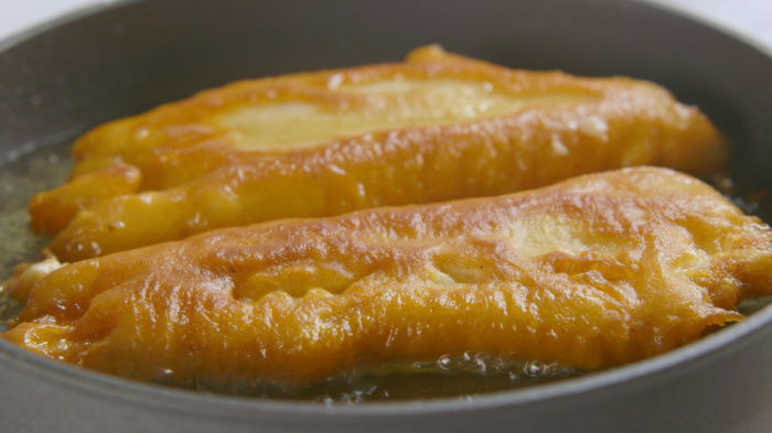 a picture of two pieces of battered fish frying in a pan
