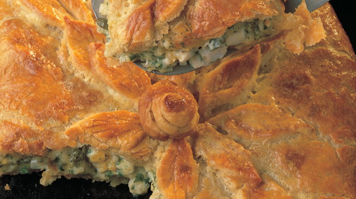 a flaky fish pie with a slice taken out showing the filling and the crumbly pastry.