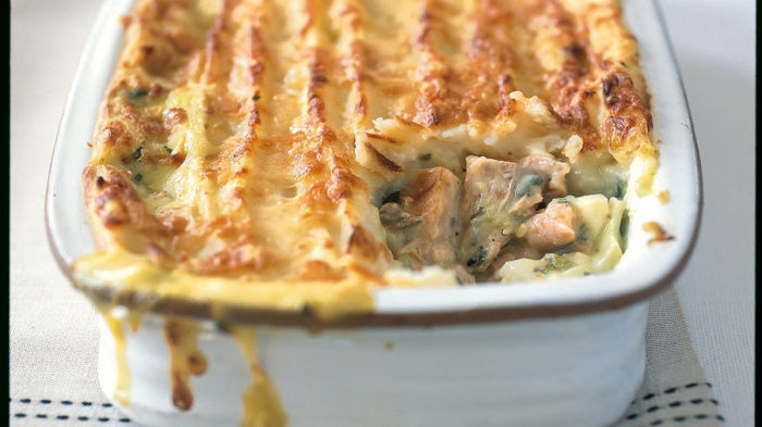 an oblong pie dish full of smoked salmon filling and a potato topping with a piece taken out of the corner