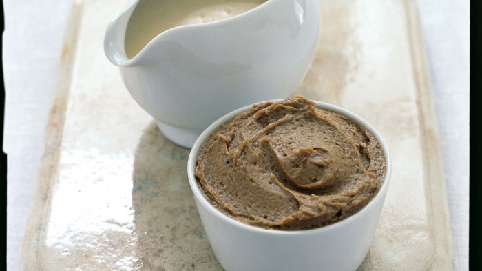 a picture of a white jug with sauce and a white dish with brandy butter sugar on a marble tray