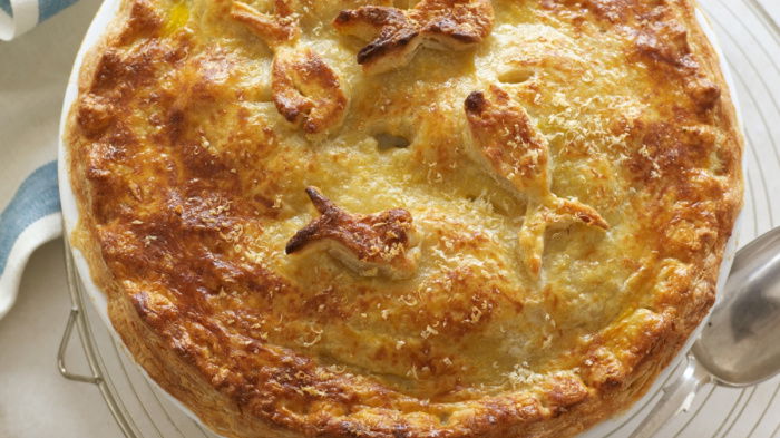 picture of Delia Smith recipe for luxury seafood pie with a parmesan crust served in white dish on wire rack with a serving spoon