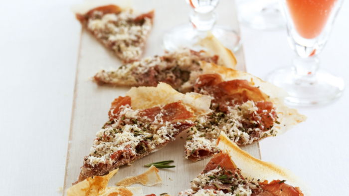 bite-sized parma ham pecorino and rosemary crisps on a wooden board with drinks