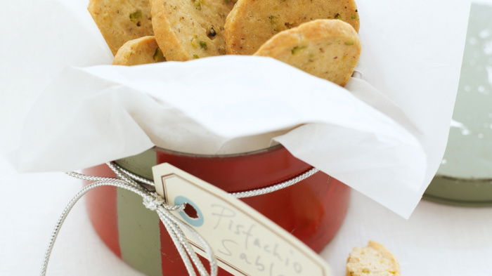 A pricture of a red tin containing little sable biscuits with one broken in half next to it