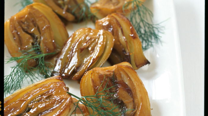 a picture of a white dish with cooked halved fennel garnished with dill