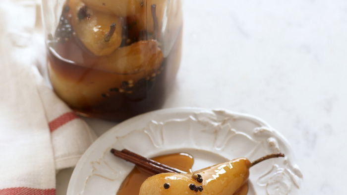 pickled pears in a glass kilner jar with a single pear on a white plate