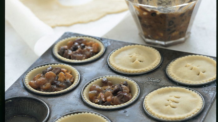 A a picture of a baking tray with pastry and mince pie filling in each hole