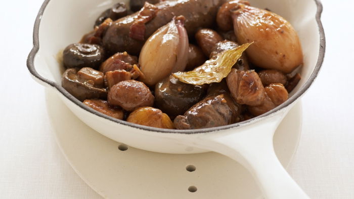 a picture of venison sausages braised in white wine in a white pan