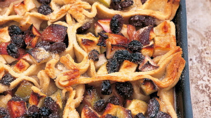 A picture of cooked apples and raisins on pastry in an oblong baking tray