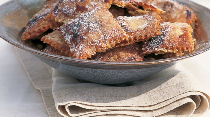 A picture of a shallow dish containing sweet filled ravioli and icing sugar sprinkled over the top