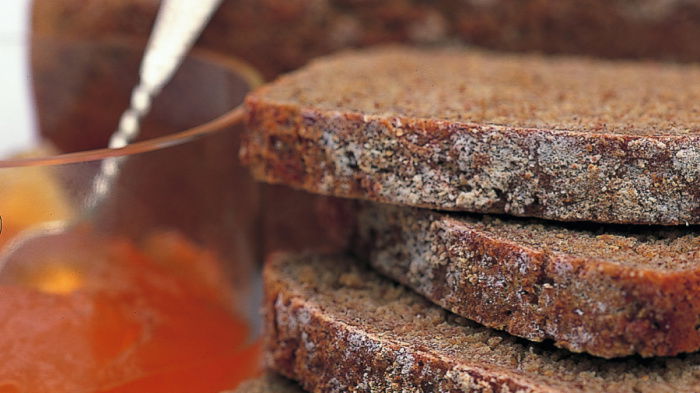 three slices of wholemeal bread next to a glass jar of marmalade