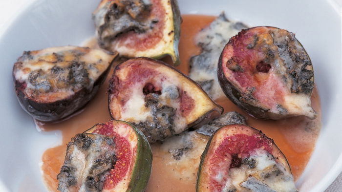 a picture of halved figs in a white dish with honey and gorgonzola drizzled on top