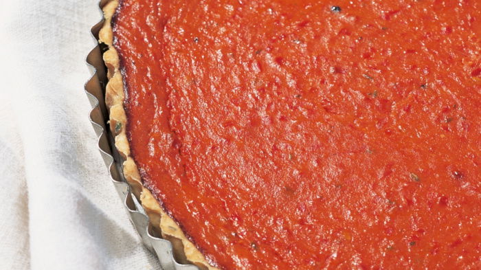 a picture of a red pepper and tomato tart in a fluted tin on a red and white tea towel