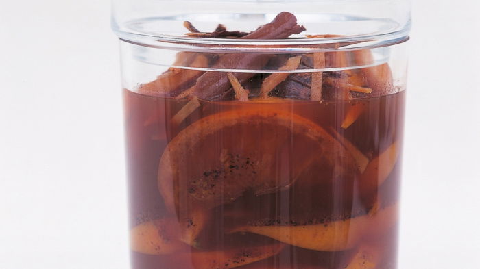 a picture of sliced oranges cinnamon sticks and cloves in a glass jar with port