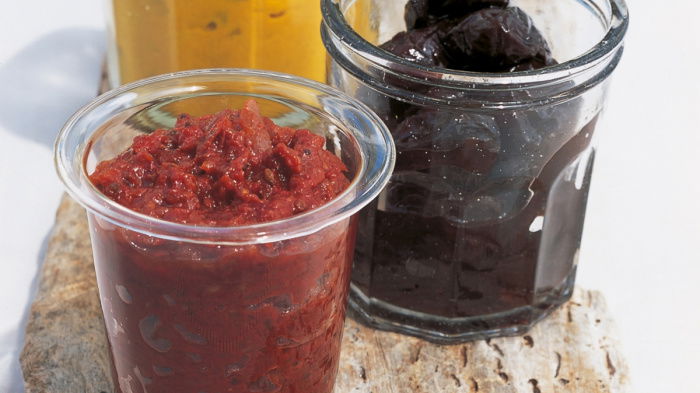 a picture of three glass jars on a wooden board with different pickles filling each one