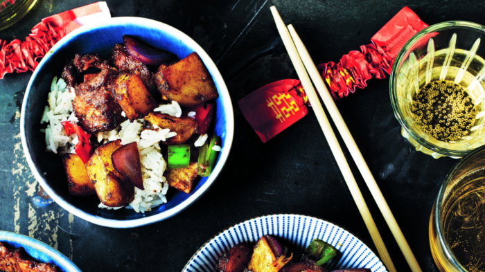 Colourful litle bowls of beef and black pepper potatoes on a black table with chopsticks resting on the side