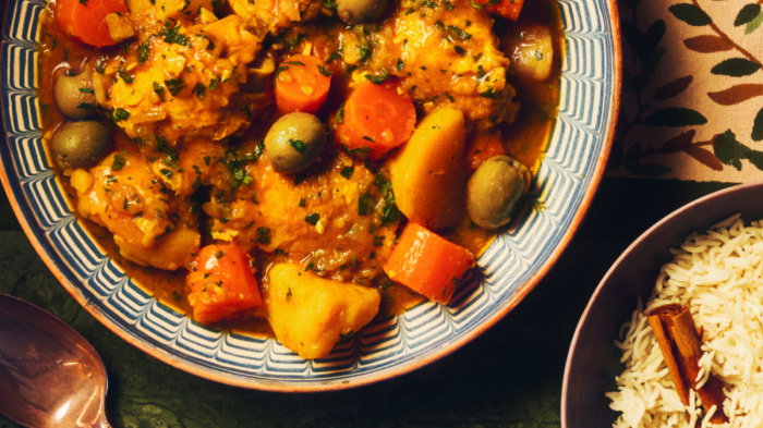 A picture of a table set with a colourful table cloth and bowls of tagine, rice and eggs 
