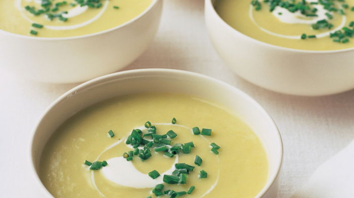 Four white bolws of leek and potatoe soup with creme fraiche swirled on top and a garnish of snipped chives