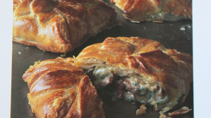 Cooked chicken feuilettes on a baking tray, with one sliced open showing the filling