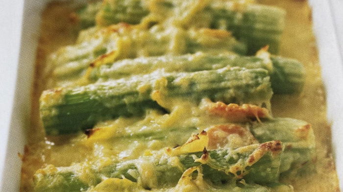 a picture of cooked slices of celery covered in cheese sauce in a white dish