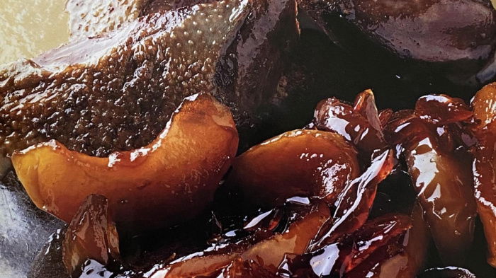 a picture of cooked wood pigeon and apples on a brown plate