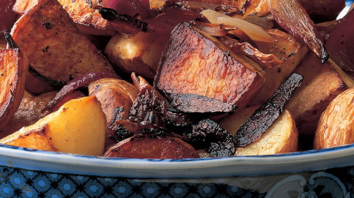 A blue and white patterend china bowl with cooked potatoes and red onion piled up