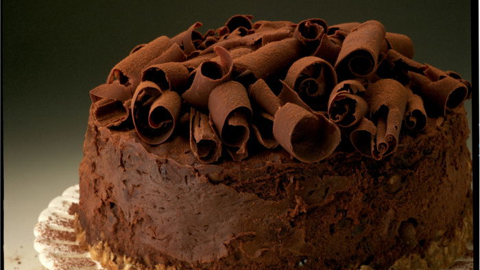 a picture of chocolate cheesecake on a white plate, with chocolate curls on the top