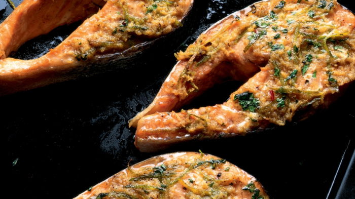 three cooked salmon steaks on a black roasting tin, with a bowl of salsa on the side