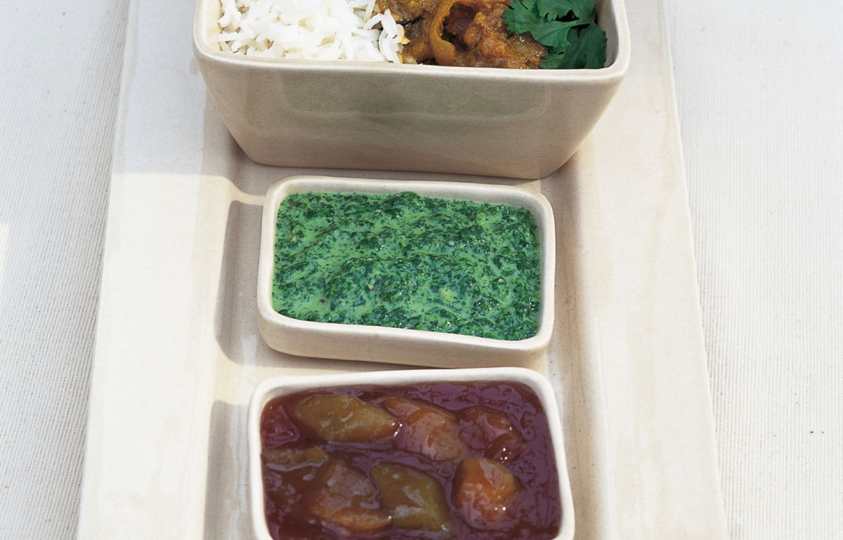 three white dishes containing beef curry rice and coriander