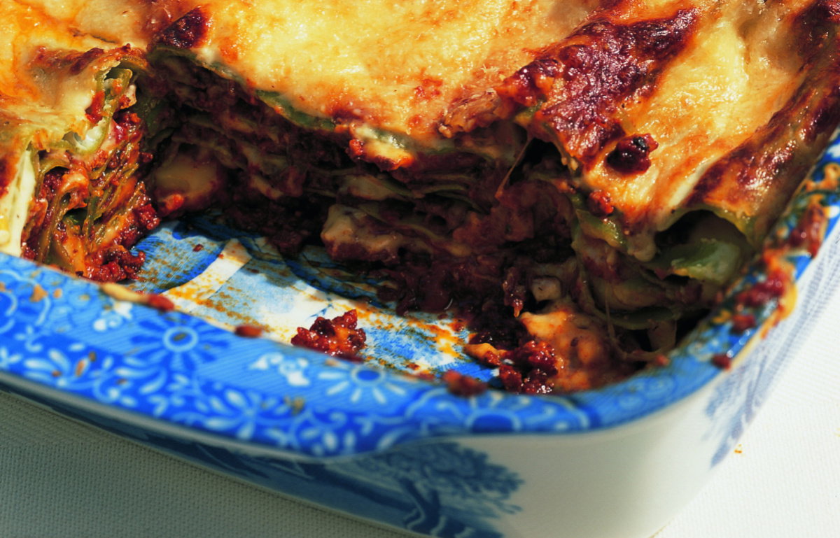 picture of a blue and white willow pattern dish containing cooked lasagne with a portion removed