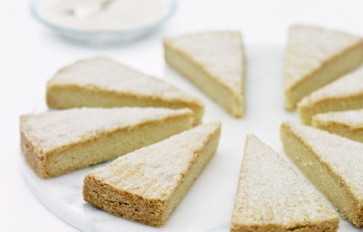 Eight slices of shortbread dusted with sugar on a whilte marble plate