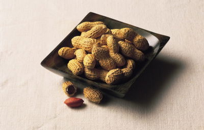 A picture of a black square dish containing peanuts in their shells