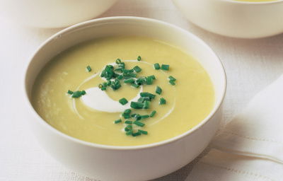 Four white bolws of leek and potatoe soup with creme fraiche swirled on top and a garnish of snipped chives
