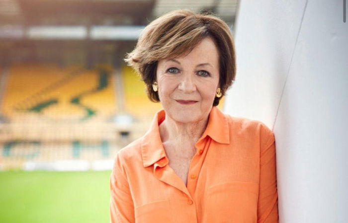 a picutre of Delia Smith in a peach shirt leaning  against the wall of the players tunnel at carrow road football club
