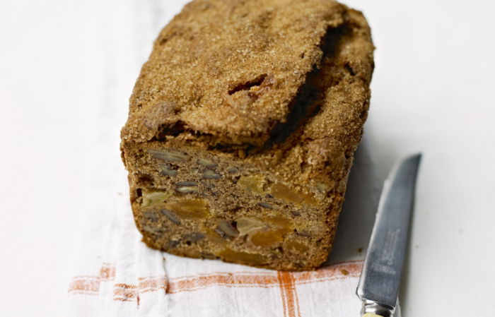 A picture of a cooked loaf cake on a red and white folded teatowel with a knife next to it