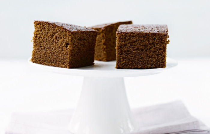 three slices of gingerbread cake on a white pedestal cake stand