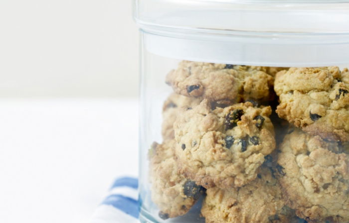 A lidded glass jar full of rock cakes on a folded blue and white napkin