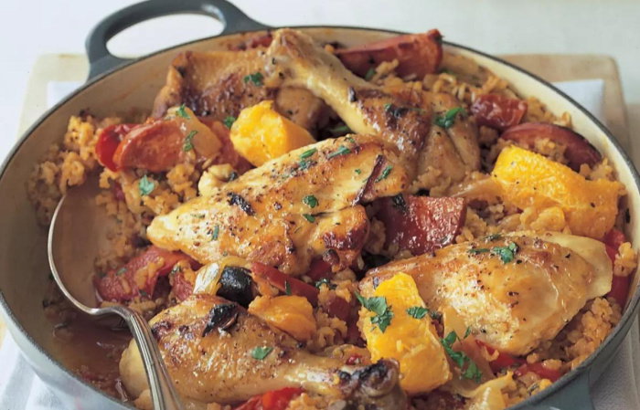 A picture of cooked chicken basque in an oven dish with a spoon resting on the side