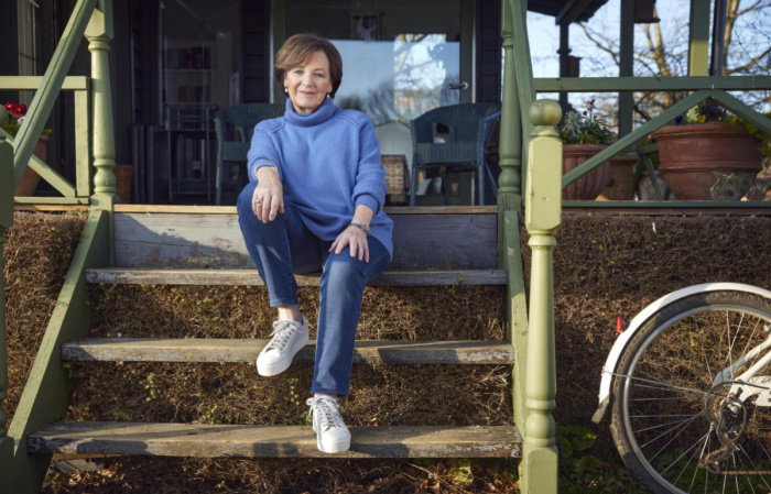 a pictur eof delia sitting on a wooden step in jeans, blue top and trainers 