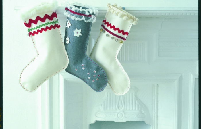 A fireplace set with logs and three different christmas stockings attached to the mantlepiece