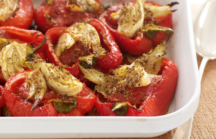 cooked red peppers and fennel in a white serving dish on a wooden serving board