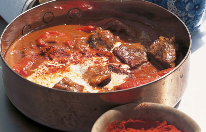 Braised beef goulash in a copper tin with a little bowl of smoked pimenton next to it and a little blue and white jug